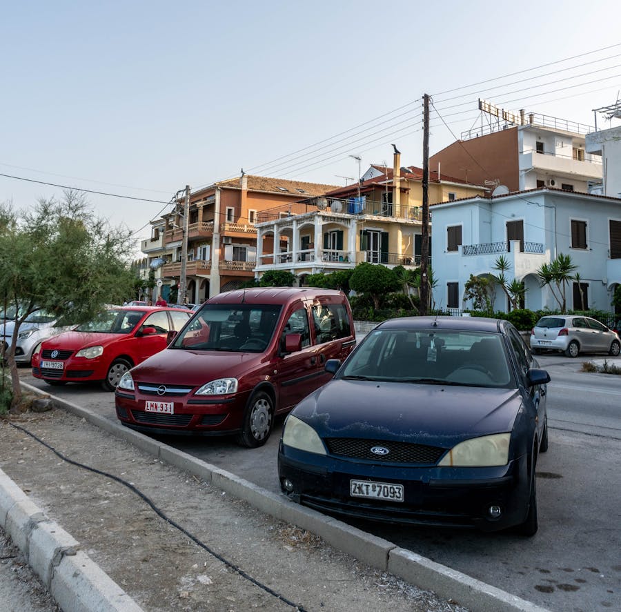 Street view of a Greek island showcasing parked cars and charming architecture
